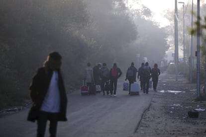 Migrantes transportan sus pertenencias fuera 'La Jungla' para registrarse en un centro cercano a Calais. 