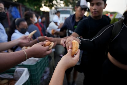 Mujeres entregan alimentos a los migrantes que viajan por la carretera a Huixtla.