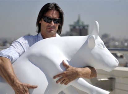 El escultor Víctor Ochoa posa con una de las vacas de la muestra