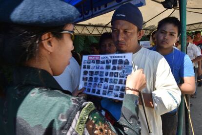 Un oficial de policia comprueba la identidad de un residente con un papel con imágenes de terroristas locales, en un puesto de control a la ciudad de Iligan, en la isla meridional de Mindanao. Las autoridades filipinas anunciaron que el número oficial de muertos durante las batallas entre militantes vinculados al ISIS y las tropas de seguridad había ascendido a 85, incluyendo civiles ejecutados y militantes islámicos extranjeros entre los muertos.