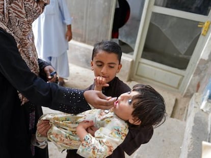 Uma trabalhadora paquistanesa vacina uma criança no Paquistão.