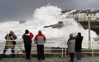 Varias personas observan el oleaje formado en el puerto de Rinlo, en Lugo. El nuevo temporal que azota desde este lunes Galicia y la cornisa cantábrica ha puesto en alerta roja el litoral del norte con rachas de viento de hasta 130 kilómetros por hora y olas de hasta 10 metros de altura, aunque castiga también a buena parte de la península.