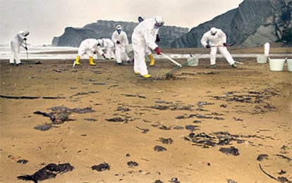 Una treintena de trabajadores se afana en la limpieza de fuel en la playa vizcaína de Sopelana.