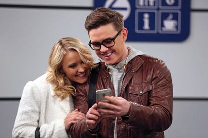 Dos de los actores de la comedia americana 'Young & Hungry' (2014), dando utilidad a su smarphone en un aeropuerto.