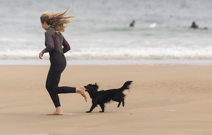 Una joven corre con su perro por la playa de la Zurriola de San Sebastián, el jueves.