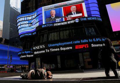Una persona duerme frente a una pantalla que muestra la cobertura de las elecciones en Times Square (Nueva York), el 6 de noviembre.