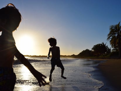 La silueta de dos chicos en la playa de Ponce contra el cielo de una puesta de sol, Puerto Rico.