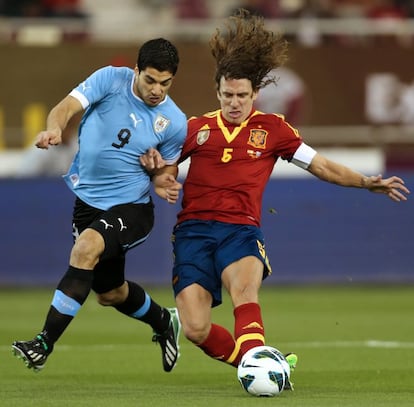 Puyol retiene el balón ante el jugador de Uruguay Luis Suárez, en el partido en el que el jugador cumple 100 partidos con la selección.