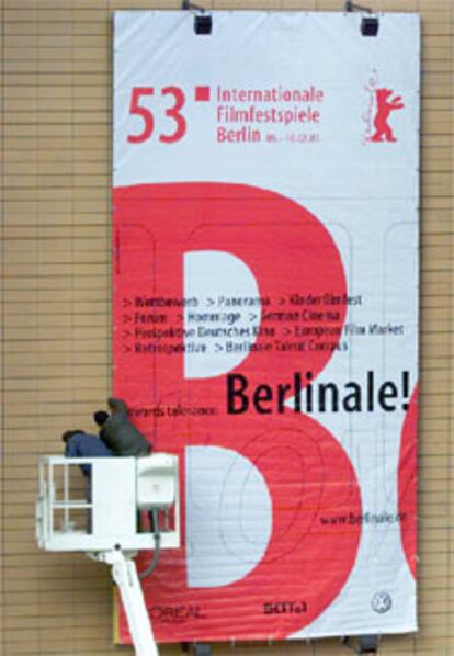 Dos operarios colocan un cartel del Festival.