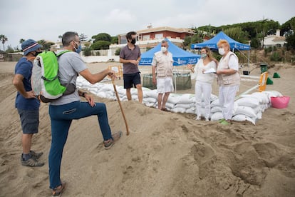 Cuatro personas voluntarias responden las dudas de dos excursionistas junto al nido de tortuga boba en Marbella.