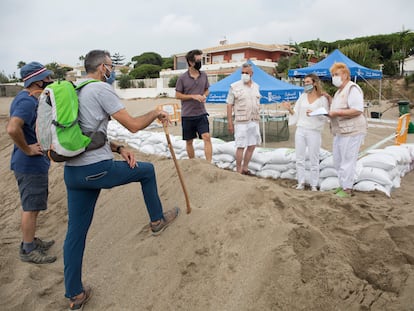 Cuatro personas voluntarias responden las dudas de dos excursionistas junto al nido de tortuga boba en Marbella.