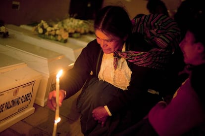 Una mujer coloca una vela junto al ataúd que contiene los restos de uno de sus familiares.