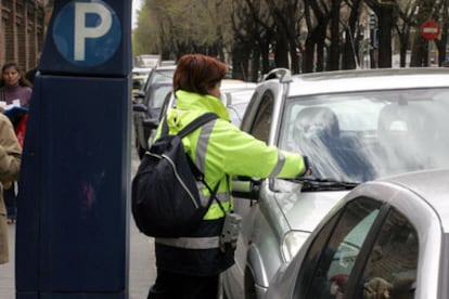 Una empleada del SER multa un vehículo en una calle de Madrid.