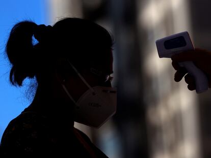 Un sanitario toma la temperatura a una mujer antes de acceder a un centro de salud.