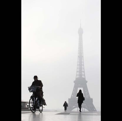 Unos ciudadanos pasean por la explanada del Trocadero frente a la Torre Eiffel, bajo un cielo cubierto por la niebla provocada por la intensa polución.