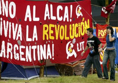 Una pareja pasa delante de una pancarta en el Campo de la Juventud instalado para el III Foro Social Mundial de Porto Alegre.