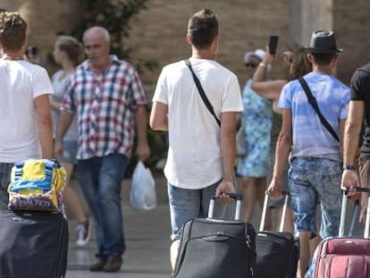 Cuatro turistas caminan con su maletas por Valencia.