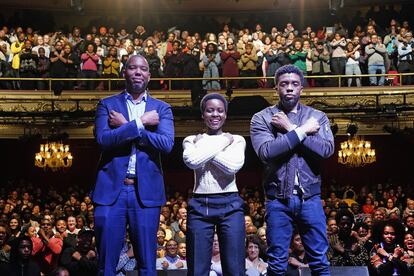 El escritor Ta-Nehisi Coates (a la izquierda) y los actores Lupita Nyong'o y Chadwick Boseman hacen el saludo 'wakanda', en el teatro Apollo de Nueva York, en febrero de 2018.