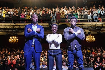 El escritor Ta-Nehisi Coates (a la izquierda) y los actores Lupita Nyong'o y Chadwick Boseman hacen el saludo 'wakanda', en el teatro Apollo de Nueva York, en febrero de 2018.