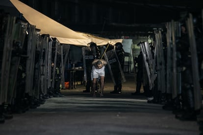 Military police with riot shields escort suspected gang members.