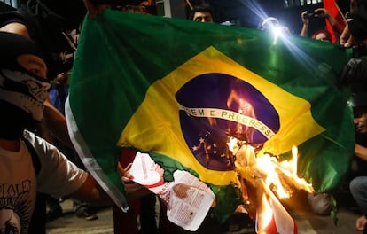 Um grupo queima uma bandeira do Brasil durante protesto contra o Mundial.