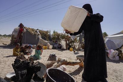 Una mujer vierte las últimas gotas de agua de una botella para preparar la comida junto a su tienda de campaña en el campo de Al-Khuseif. La familia trae agua potable en botellas desde lejos porque no hay en la zona.