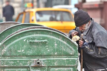 Un hombre recoge pan de un contenedor de basura ayer en Bucarest.