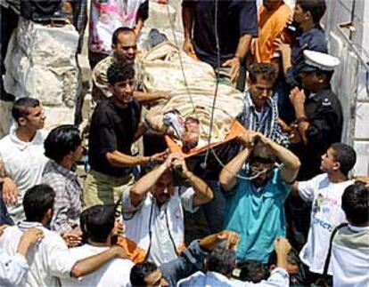 Habitantes palestinos de Nablús ayudan a evacuar el cadáver de una de las ocho víctimas del ataque de los helicópteros israelíes.