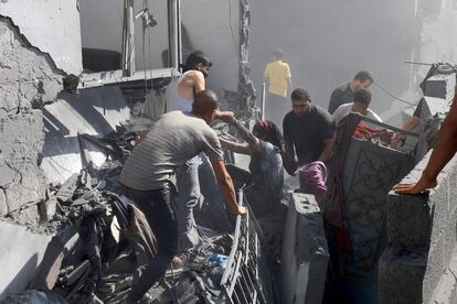 Voluntarios rescataban a una mujer de entre los escombros de un edificio tras un ataque israelí en Jan Yunis, este jueves. 