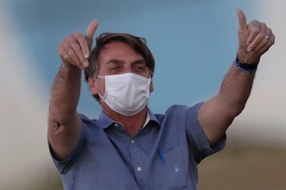 El presidente de Brasil, Jair Bolsonaro, con mascarilla y los pulgares en alto saluda al público a las afueras de su residencia en Brasilia el pasado 17 de julio poco después de conocerse su contagio por covid-19