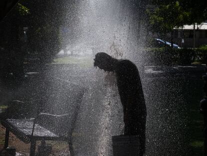 Un hombre se refresca con agua de riego en un parque en San Luis Río Colorado (México), el 13 de julio del 2023.