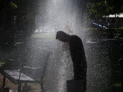 Un hombre se refresca con agua de riego en un parque en San Luis Río Colorado (México), el 13 de julio del 2023.