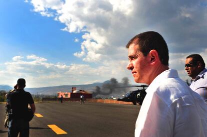 El comisionado para Michoacán, Alfredo Castillo, regresa a Morelia de Apatzingán. Al fondo, el humo de un incendio aislado en la capital michoacana.