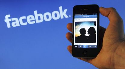 Un teléfono inteligente con el logo de facebook detrás.
