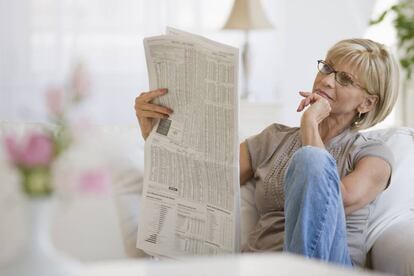 Una mujer leyendo el peri&oacute;dico.