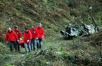 Miembros de los equipos de rescate trasladan el cadáver de uno de los fallecidos en el accidente aéreo.