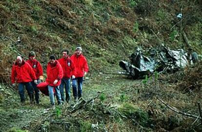 Miembros de los equipos de rescate trasladan el cadáver de uno de los fallecidos en el accidente aéreo.