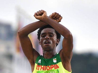 Feyisa Lilesa faz o gesto crítico ao cruzar a linha de chegada.