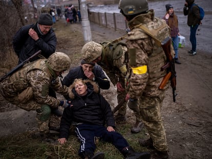 A semi-conscious woman is attended to by Ukrainian soldiers after crossing the Irpin river as fleeing the city in the outskirts of Kyiv, Ukraine, Saturday, March 5, 2022. (AP Photo/Emilio Morenatti)