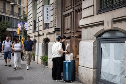 Dos turistas frente a un portal a punto de entrar en un piso turístico en la Calle Roger de Lluria del barrio del Eixample de Barcelona, en junio de 2024.