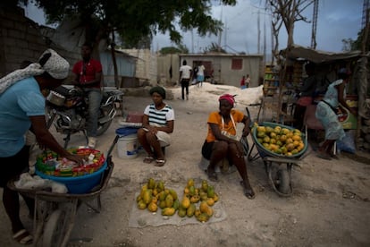 Unas mujeres venden mangos y otros alimentos básicos en una encrucijada llenas de tiendas y puestos de venta en Canaan, Haití. Las pequeñas empresas establecidas por los colonos han surgido por toda la ciudad y atienden a las necesidades diarias de los residentes de siempre y de quienes han llegado con el auge de la construcción.