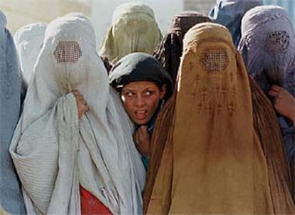 Con la llegada al poder de los talibán, las mujeres afganas se vieron obligadas a vestir el tradicional burka, que tiene una rejilla a la altura de los ojos que les permite ver. En la imagen, una muchacha mira a cara descubierta entre las mujeres ocultas. (18/10/1997)
(AP)