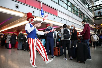 Un artista hace malabares junto a una fila de viajeros de los vuelos de Virgin Atlantic y Delta Air Lines en Londres con destino a Estados Unidos.