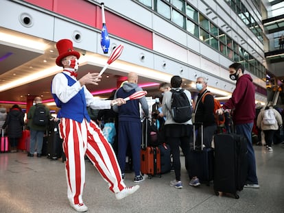Un artista hace malabares junto a una fila de viajeros de los vuelos de Virgin Atlantic y Delta Air Lines en Londres con destino a Estados Unidos.
