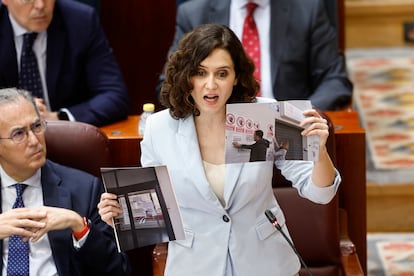 La presidenta de la Comunidad de Madrid, Isabel Díaz Ayuso, muestra fotos de centros de salud con carteles reivindicativos durante el pleno de la Asamblea.