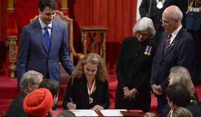 Julie Payette firma su cargo ante la mirada del primer ministro, Justin Trudeau.