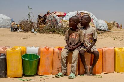 Dos niños esperan sentados a que se pueda empezar a recibir agua en Kindjandji.