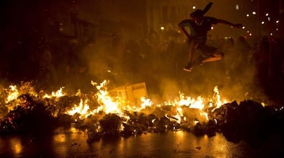 Un miembro de los Black Bloc salta encima de una barricada ardiendo en Rio de Janeiro.