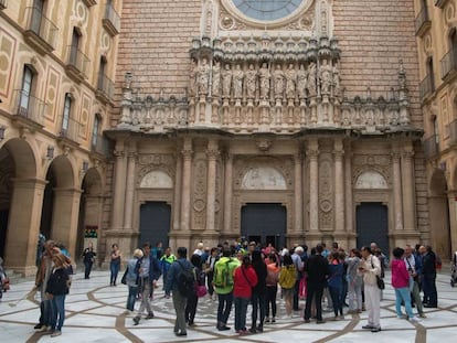 Diversos turistes i feligresos congregats davant de les portes del monestir de Montserrat.