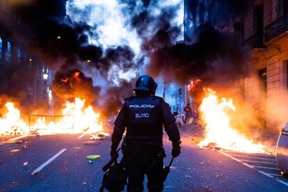 Um policial caminha entre barricadas em chamas perto da delegacia da Via Laietana, que foi um dos pontos de maior conflitos das jornadas de Barcelona.